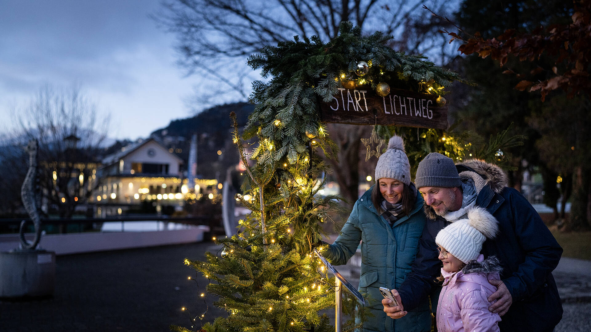Familie am Millstaetter Lichtweg im Advent neben dem Christbaum